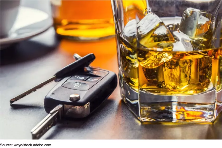 Photo showing a glass of brown liquor and ice with a set of car keys just next to it.
