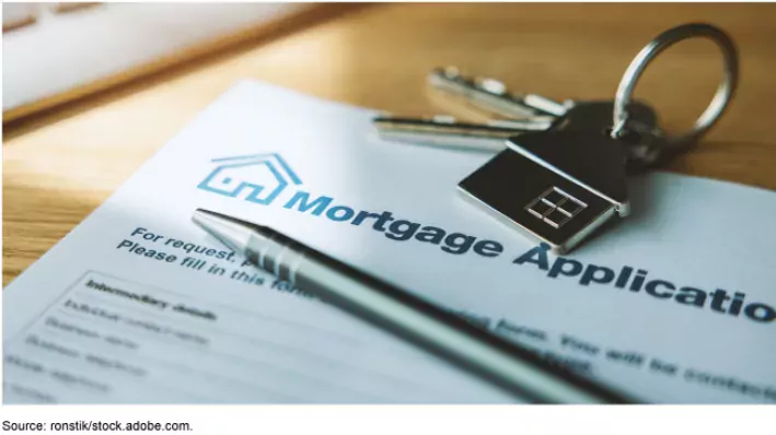 Stock art image showing a mortgage application on a desk with house keys and a pen sitting on top.