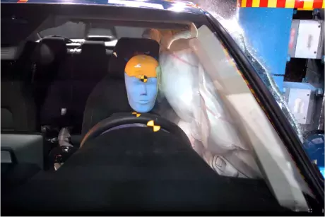 Photo showing a crash dummy behind the steering wheel of a car with the side air bag filled.