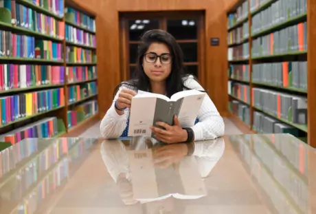 Photo of Someone Reading a Book in a Library