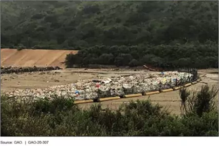 Plastic bottles, tires, and other debris caught behind a trash rack, Tijuana River, United States