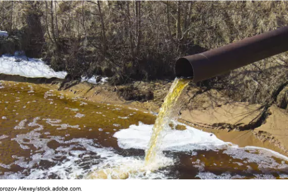 Photo showing water coming out of a pipe with pollution dumping into a stream