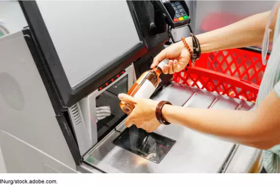 Photo of a woman using a self-check-out machine in a grocery store