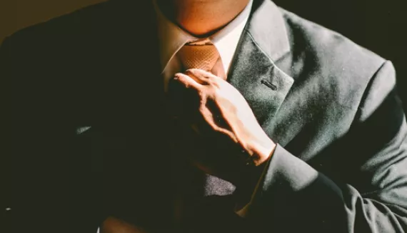 A shot of the chest of a man in a suit straightening his tie.