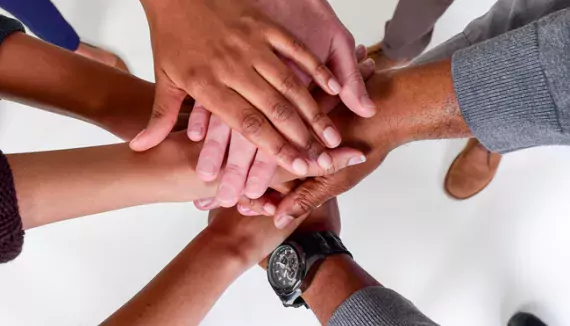 Photo of a huddle of hands representing diverse group